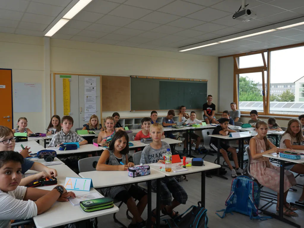 Blick durch den Klassenraum auf die arbeitenden Kinder.
